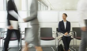 Woman in Suit sitting in the busy workplace