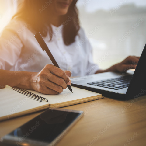 Woman taking notes with Laptop